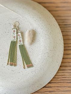 two tasseled earrings on a white plate