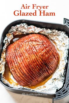 an air fryer glazed ham in a pan with foil on the side and text overlay