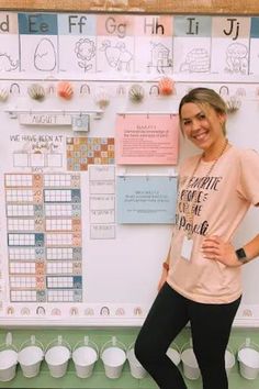 a woman standing in front of a bulletin board with writing on it and cups around her