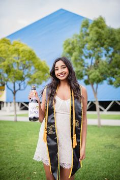 a woman wearing a graduation gown and holding a bottle of booze in her hand