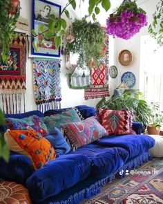 a living room filled with lots of colorful pillows and hanging planters on the wall