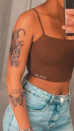 a woman with tattoos on her arm taking a selfie