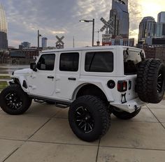 a white jeep parked in front of a city skyline