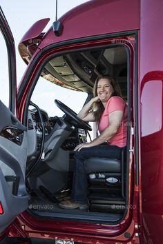 a woman sitting in the driver's seat of a red truck