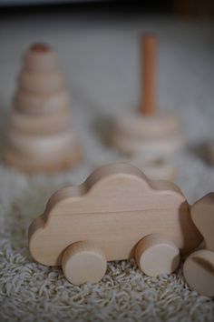 wooden toy cars sitting on top of a white carpet next to two small wooden pegs