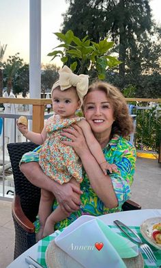 a woman holding a baby sitting at a table