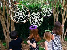 three children are standing in front of some fake spider webs on the ground and trees