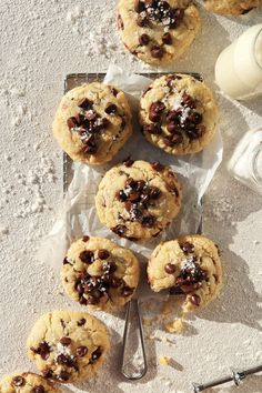 chocolate chip cookies on a baking sheet next to a glass of milk and utensils