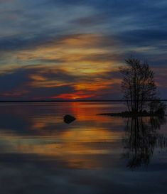 the sun is setting over an island in the middle of the water with trees on it