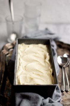 a pan filled with white frosting next to silverware