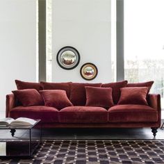 a living room with a red couch and two round mirrors on the wall above it