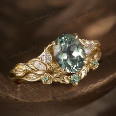 a ring with an oval green stone surrounded by leaves and diamonds on a wooden surface