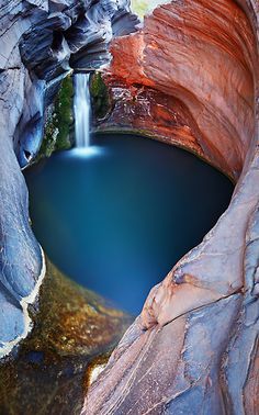 there is a small waterfall in the middle of this lake with blue water and rocks