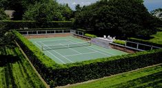 an aerial view of a tennis court surrounded by hedges