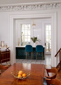 a dining room table with chairs and fruit bowl on it