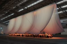 a large group of people standing in front of a giant white sheet covered structure at night