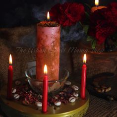 a lit candle sitting on top of a bowl filled with nuts next to red flowers