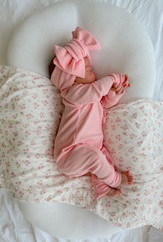 a baby laying on its back in a pink outfit