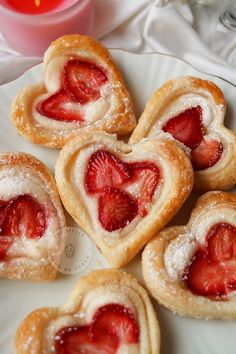 some heart shaped pastries are on a plate with strawberries in the shape of hearts