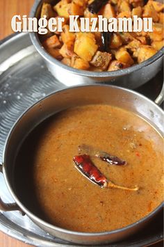 two metal pans filled with food sitting on top of a wooden table next to each other