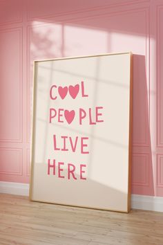 a pink room with a white framed poster on the wall that says cool people live here