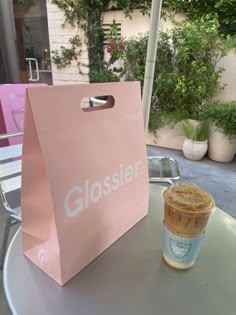 a pink shopping bag sitting on top of a table next to a cup of coffee