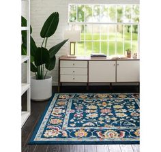 a blue rug in front of a window with a potted plant next to it