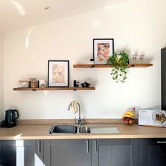 a kitchen with wooden counters and shelves above the sink, along with pictures on the wall