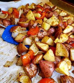 potatoes and tomatoes on a baking sheet with a spatula