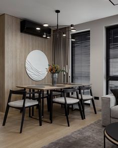 a dining room table with chairs and a round mirror on the wall in front of it