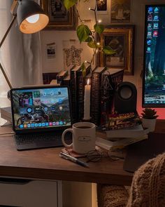 a laptop computer sitting on top of a wooden desk next to a cup of coffee