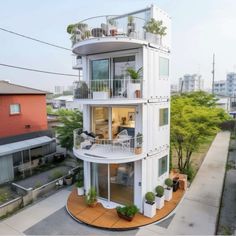 a large white building with balconies and plants on the top floor in front of it