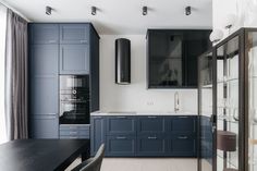 a modern kitchen with blue cabinets and black counter tops, along with a dining room table