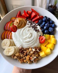 a white plate topped with fruit and yogurt next to sliced bananas, strawberries