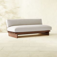 a white couch sitting on top of a tile floor next to a wooden frame wall