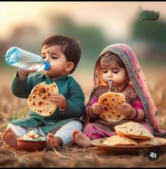 two small children sitting on the ground eating food and drinking water from a plastic bottle