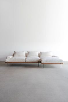 a white couch sitting on top of a cement floor next to a wall with no one in it