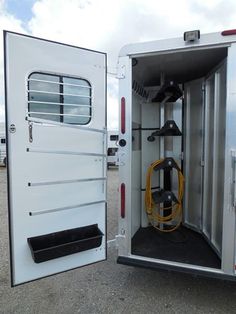 the inside of a horse trailer with its door open and a hose connected to it