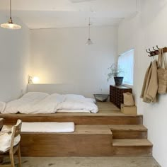 a bed sitting on top of wooden steps in a bedroom next to a table and chair