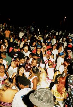 a large group of people standing around each other at a concert or gathering in the dark