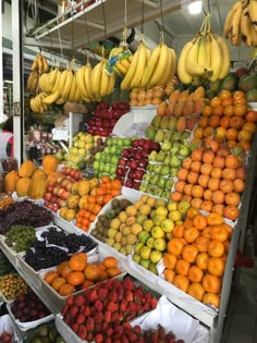 a fruit stand with lots of fruits and bananas hanging from it's sides in a market