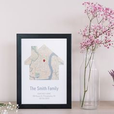 a vase filled with flowers next to a framed map and pink flowers on top of a table