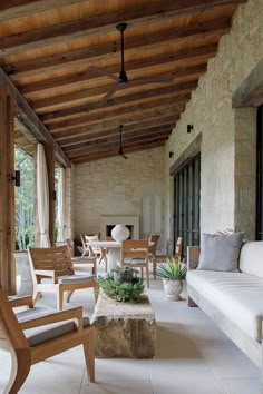 an outdoor living room with wooden furniture and stone walls