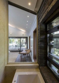 a bath tub sitting under a window next to a wooden table with chairs on it