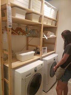 a woman standing next to a washer and dryer in a room with shelving