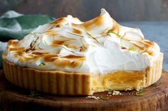 a pie with whipped cream on top sits on a wooden board