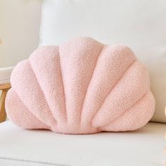 a pink pillow sitting on top of a white couch next to a stuffed animal toy