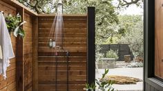 an outdoor shower in the middle of a wooden fenced area with plants and towels hanging on it