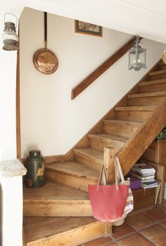 there is a red bag on the stairs in this house with wood floors and white walls