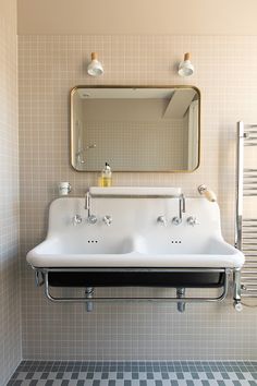 a bathroom with two sinks and a mirror on the wall above it is tiled flooring